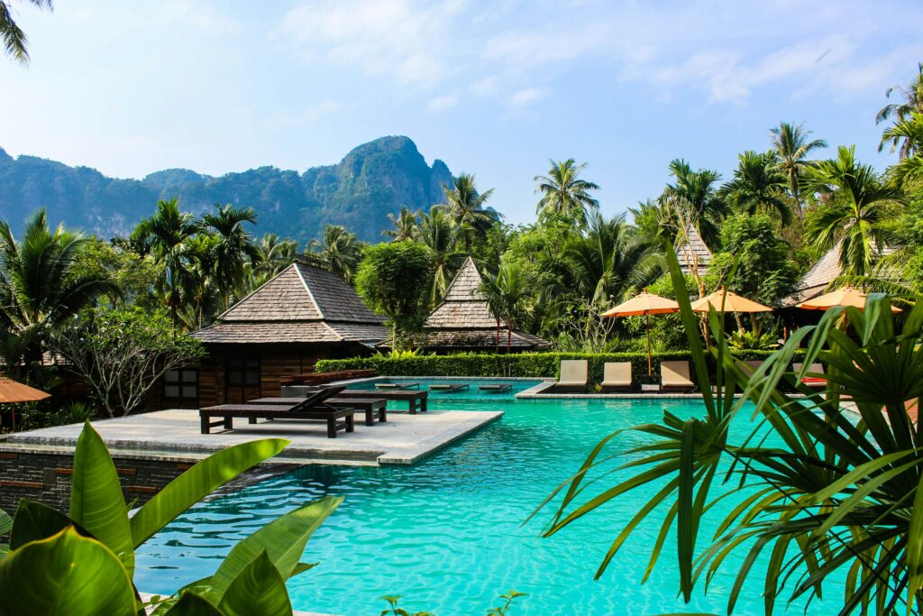 Image de transat en bois près d'une piscine avec la faune tropicale qui l'entoure Thaïlande Ao Nang